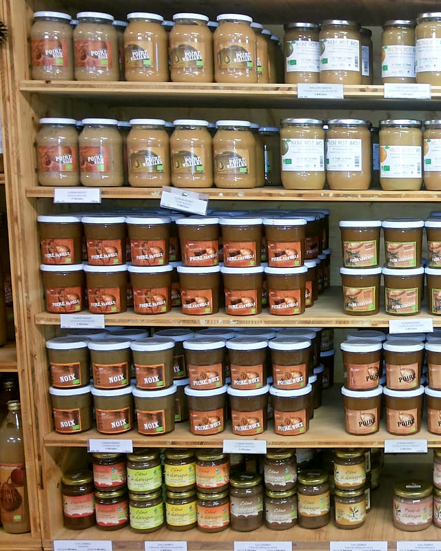 Étagères en bois remplies de bocaux de compotes, de terrines et de conserves