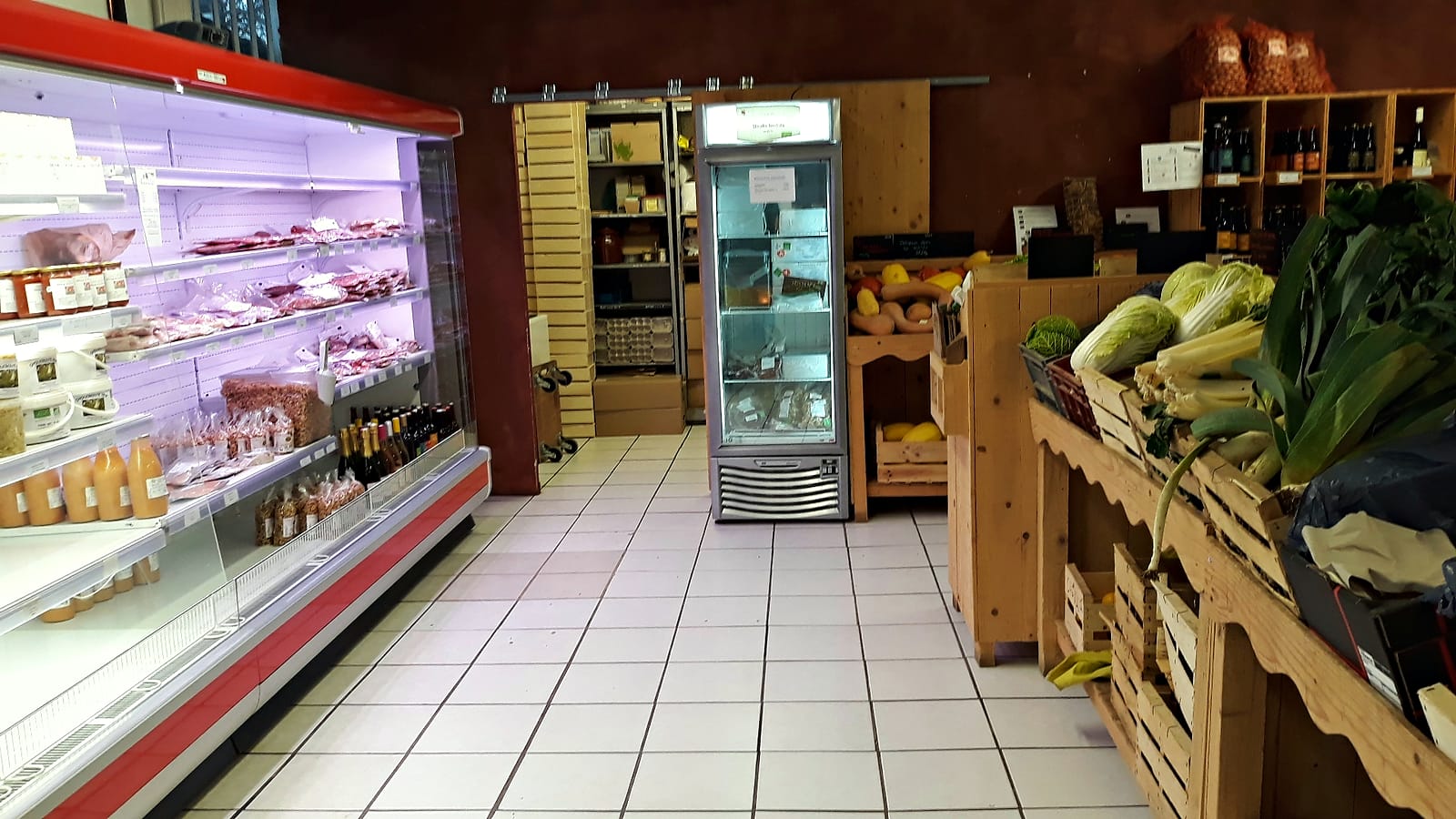 L'intérieur du magasin : étals de légumes en bois et vitrines réfrigérées